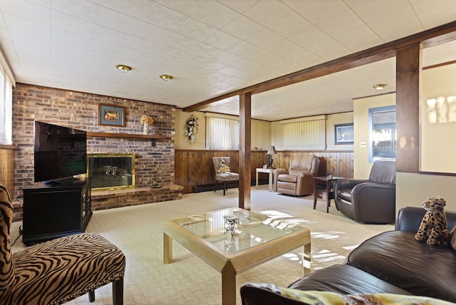 carpeted living room featuring wood walls and a fireplace