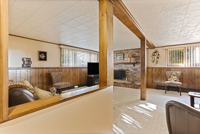 living room featuring carpet flooring, a healthy amount of sunlight, wooden walls, and a brick fireplace