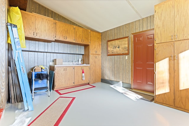 misc room featuring concrete floors, vaulted ceiling, and wood walls