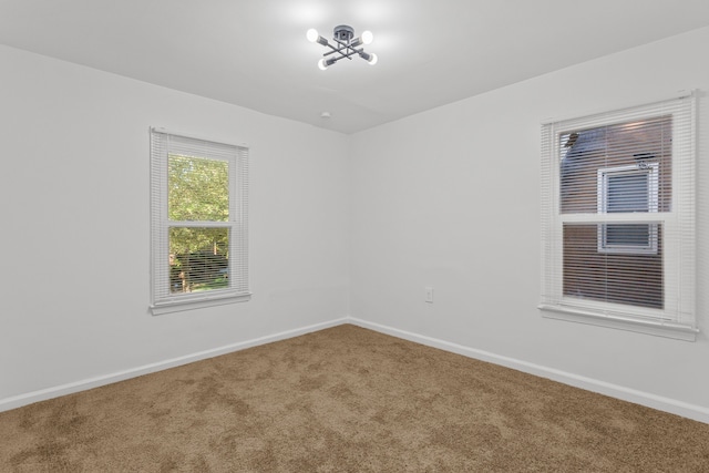 carpeted empty room featuring a chandelier