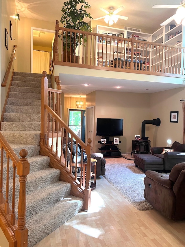 staircase with hardwood / wood-style flooring, a wood stove, and ceiling fan