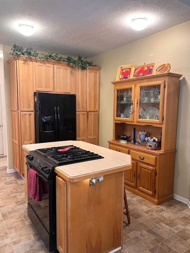 kitchen featuring black appliances, a kitchen breakfast bar, a kitchen island, and a textured ceiling