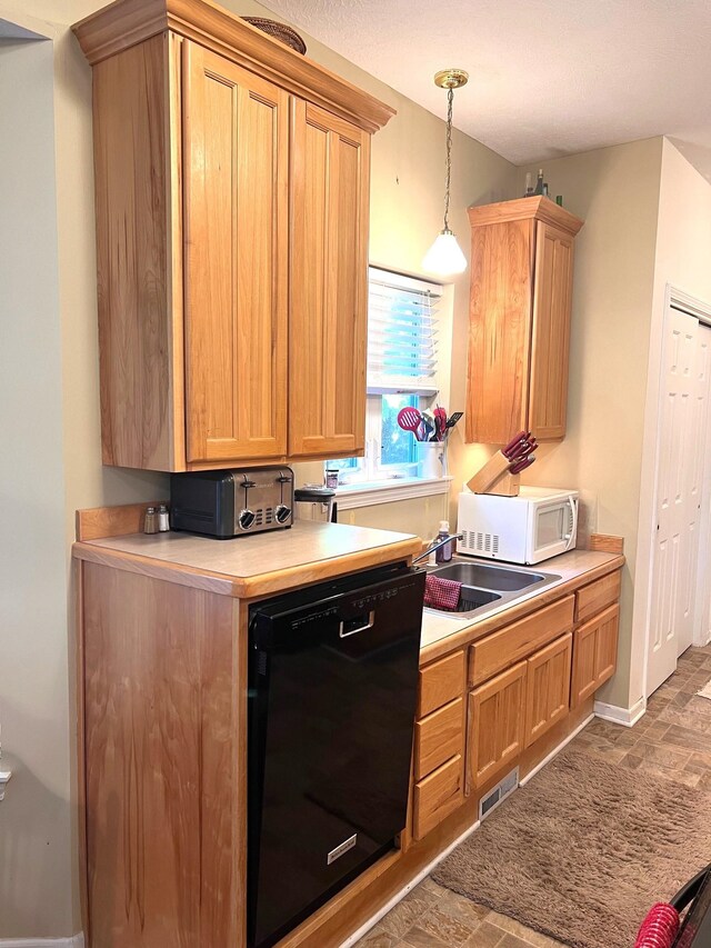 kitchen with a textured ceiling, black dishwasher, decorative light fixtures, and sink