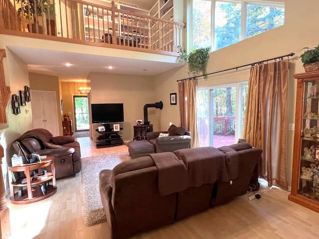 living room featuring hardwood / wood-style flooring, a wood stove, and a high ceiling