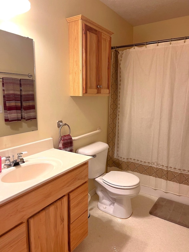 bathroom with a textured ceiling, vanity, and toilet