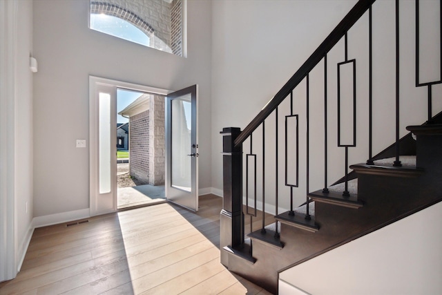 foyer entrance with wood-type flooring, french doors, and a healthy amount of sunlight