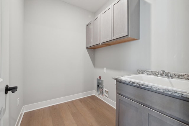 laundry area with hookup for a washing machine, cabinets, light hardwood / wood-style flooring, and sink