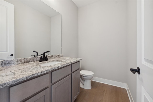 bathroom with toilet, wood-type flooring, and vanity