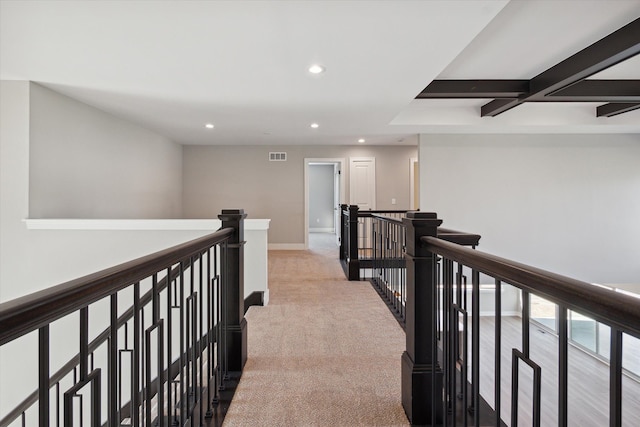 hallway with coffered ceiling, beamed ceiling, and light colored carpet