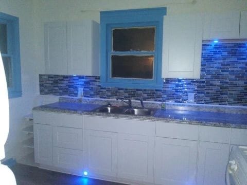 kitchen featuring decorative backsplash, white cabinetry, and sink