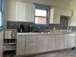 kitchen featuring white cabinets, light stone countertops, and sink