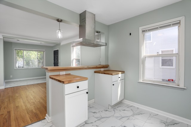 kitchen with island exhaust hood, white cabinets, a wealth of natural light, and butcher block counters