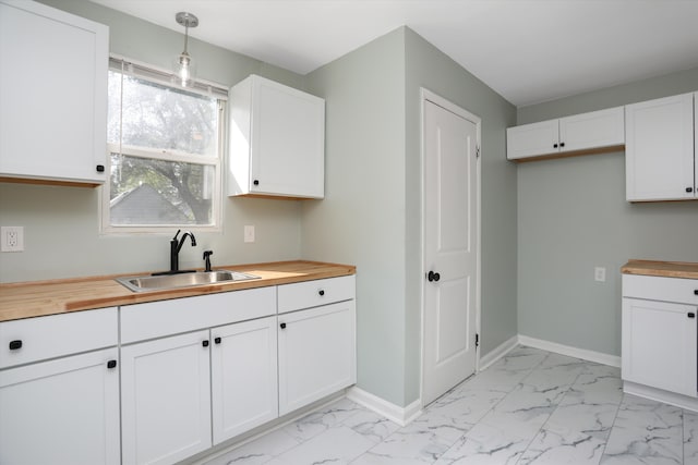 kitchen featuring wooden counters, white cabinets, and pendant lighting