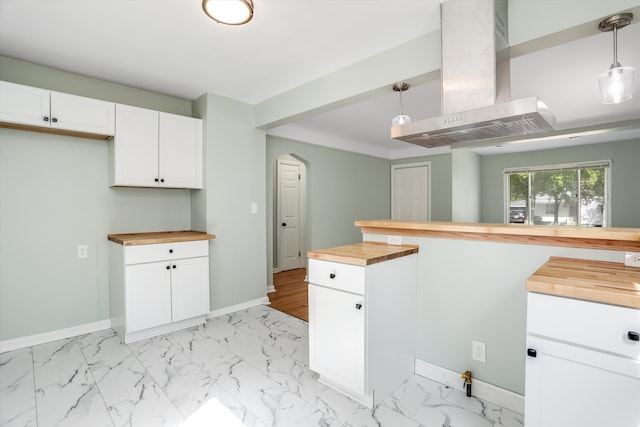 kitchen featuring butcher block counters, white cabinets, extractor fan, and decorative light fixtures