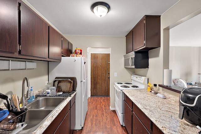 kitchen with white appliances, dark brown cabinetry, dark wood-type flooring, and sink