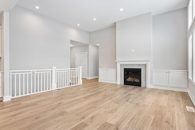 unfurnished living room featuring light hardwood / wood-style floors and a tiled fireplace