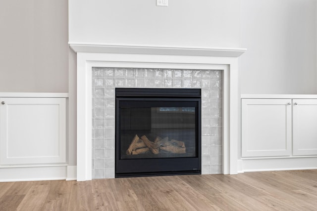 room details featuring wood-type flooring and a tiled fireplace