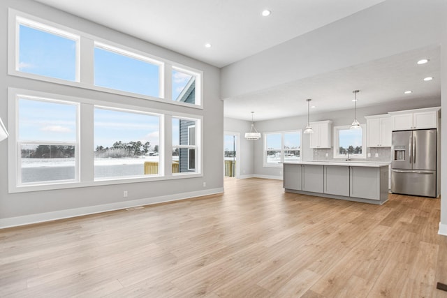 unfurnished living room with light hardwood / wood-style floors, a water view, a towering ceiling, and sink