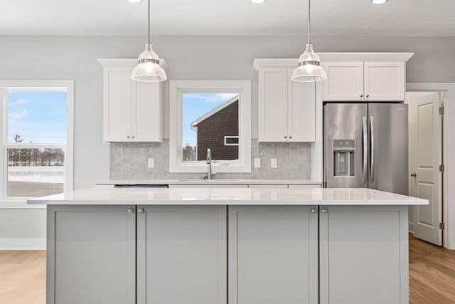 kitchen featuring white cabinetry, stainless steel fridge, a center island, and sink