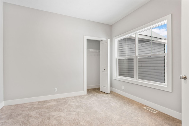 unfurnished bedroom featuring light carpet and a closet