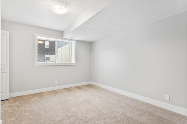 spare room featuring a textured ceiling and light colored carpet