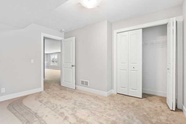 unfurnished bedroom with a closet and light colored carpet