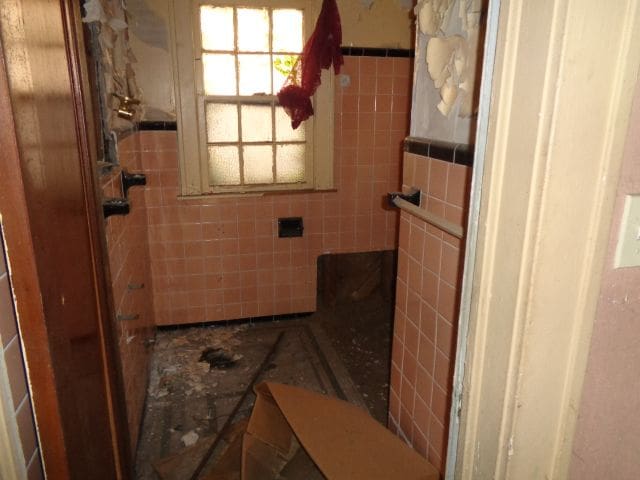 bathroom with a tile shower and tile walls