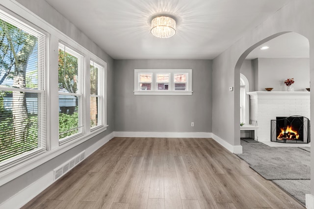 unfurnished living room featuring light hardwood / wood-style floors, a fireplace, and a wealth of natural light