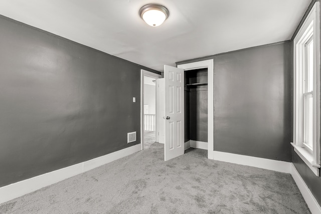 unfurnished bedroom with light carpet and a closet