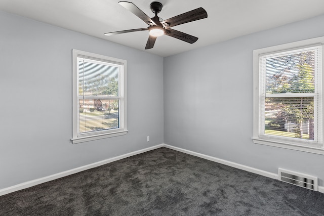 spare room with ceiling fan and dark carpet