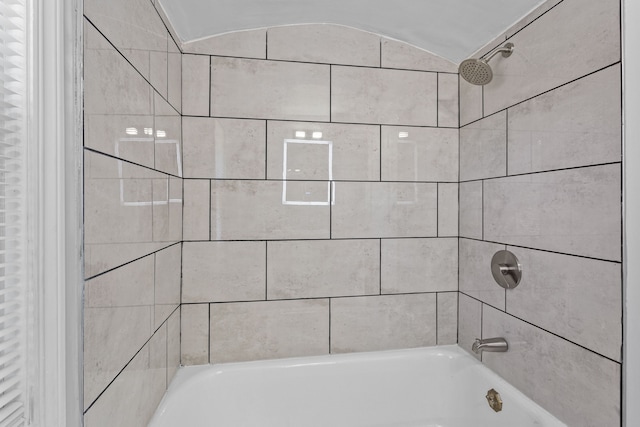 bathroom featuring tiled shower / bath combo and vaulted ceiling