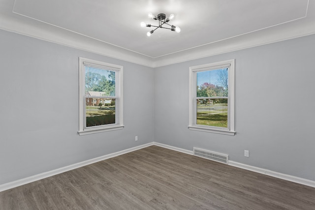 spare room with an inviting chandelier, dark wood-type flooring, and crown molding