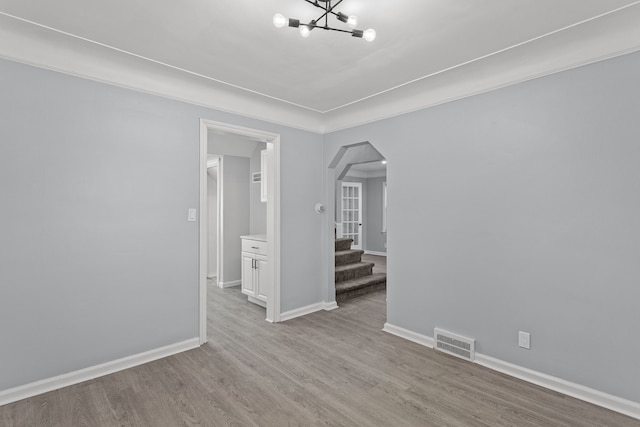 empty room featuring light hardwood / wood-style flooring and an inviting chandelier