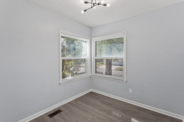 unfurnished room with dark wood-type flooring and a notable chandelier