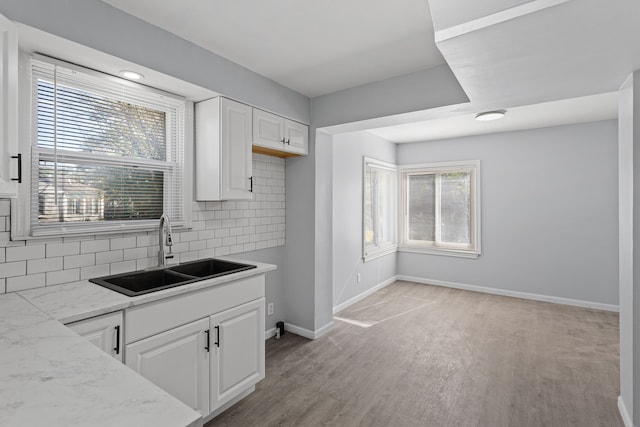 kitchen featuring decorative backsplash, a wealth of natural light, sink, and white cabinets