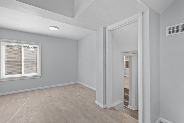 unfurnished room featuring vaulted ceiling and light hardwood / wood-style flooring