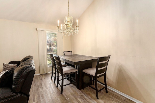 dining room featuring a chandelier, hardwood / wood-style floors, and vaulted ceiling