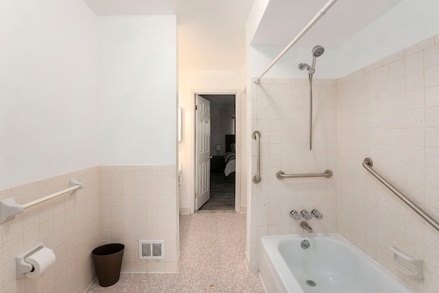 bathroom featuring tile patterned flooring, tile walls, and tiled shower / bath