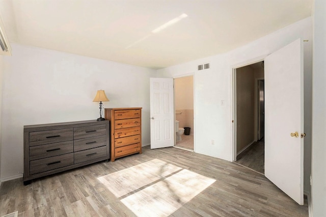 unfurnished bedroom with connected bathroom and light wood-type flooring