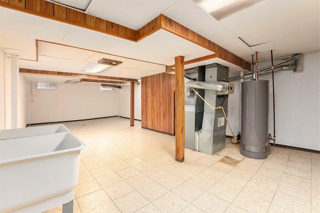 basement featuring gas water heater, heating unit, and sink