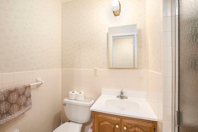 bathroom featuring vanity, a shower with door, toilet, and tile walls