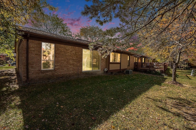 property exterior at dusk featuring a lawn and a wooden deck