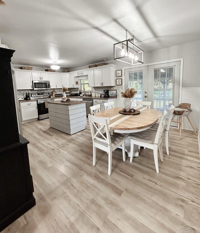 dining area featuring a chandelier, french doors, and light hardwood / wood-style flooring