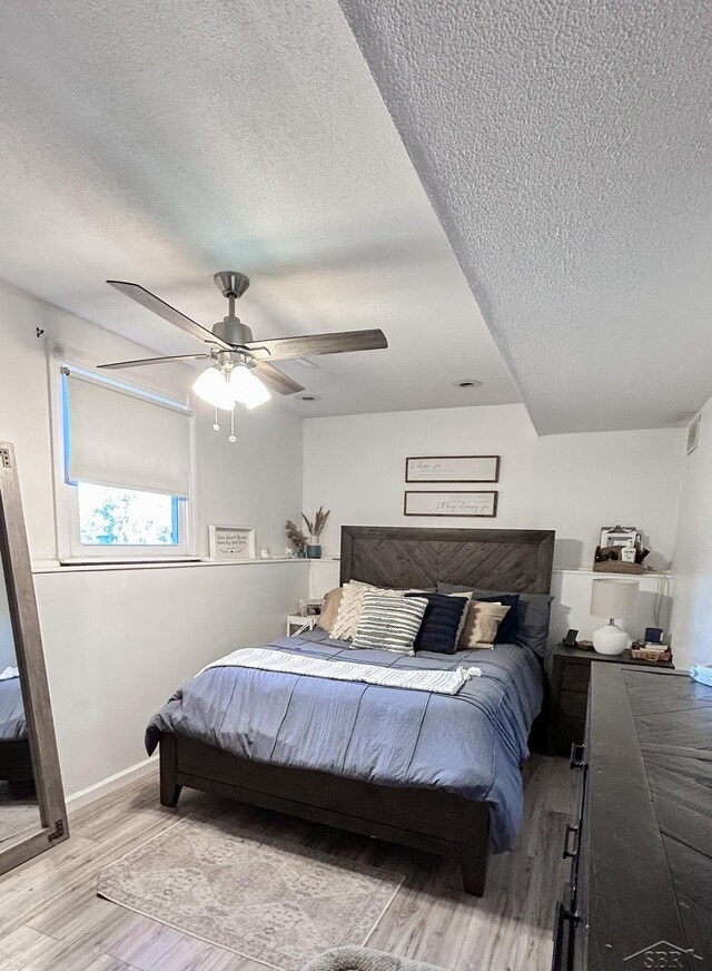 bedroom featuring ceiling fan, a textured ceiling, and light hardwood / wood-style flooring