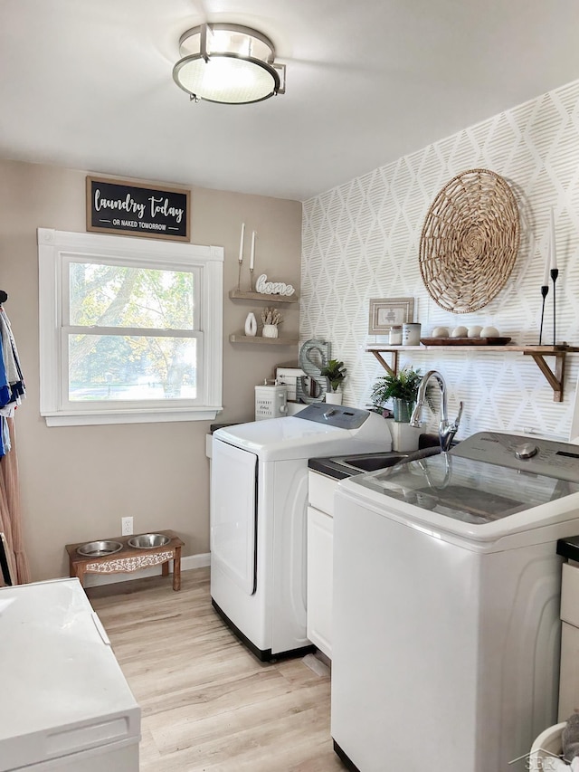 washroom featuring separate washer and dryer, light hardwood / wood-style flooring, and cabinets