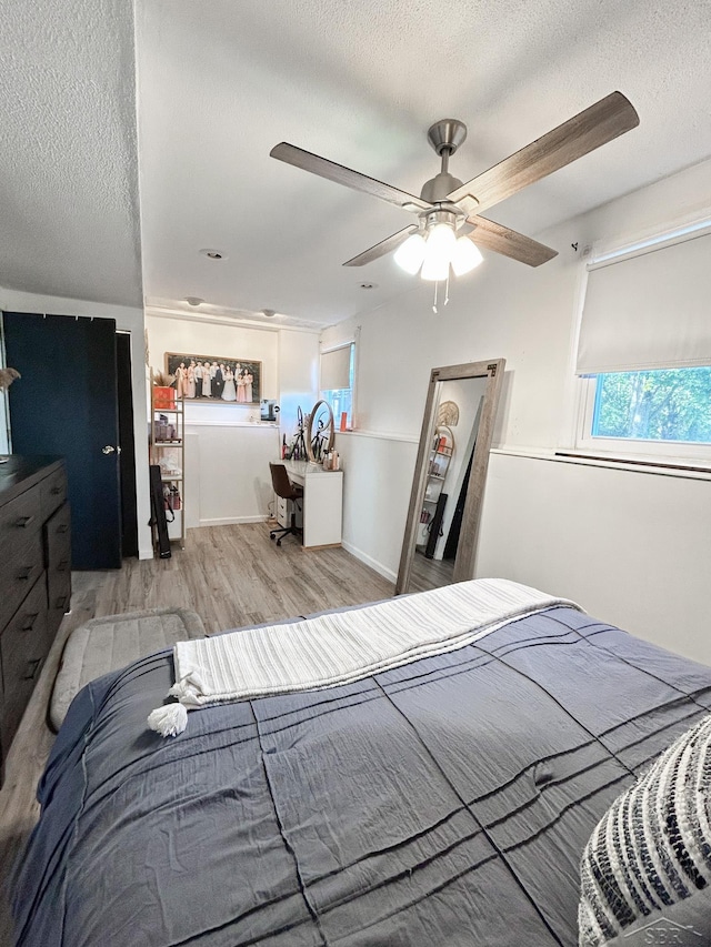 bedroom with a textured ceiling, light wood-type flooring, and ceiling fan