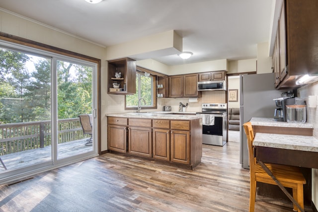 kitchen featuring sink, crown molding, light hardwood / wood-style floors, decorative backsplash, and appliances with stainless steel finishes