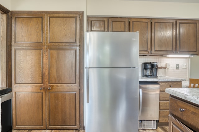 kitchen with decorative backsplash, light hardwood / wood-style flooring, and stainless steel refrigerator