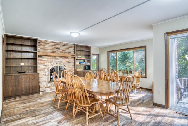 dining room with a brick fireplace, a wealth of natural light, and light hardwood / wood-style flooring