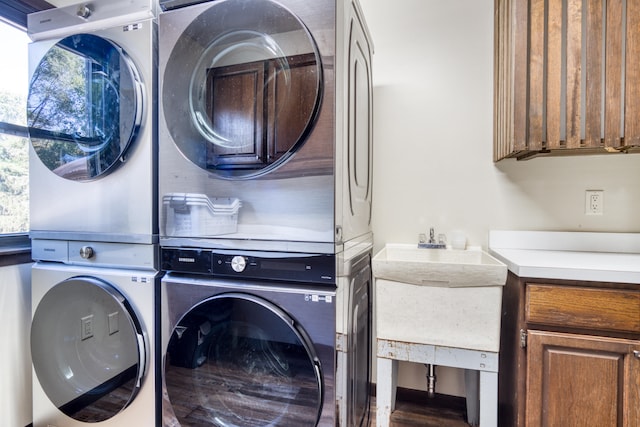 laundry room with cabinets and stacked washing maching and dryer